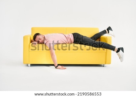 Funny frustrated exhausted man sleeping on sofa over white background. Rest, overworked concept