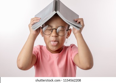 funny girl with a book on her head is showing her tongue to the camera isolated white background.