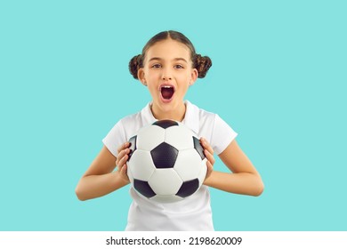 Funny girl child isolated on blue studio background hold ball cheer support sport team. Happy excited teen kid scream and yell for favorite football team goal score. Children hobby concept.