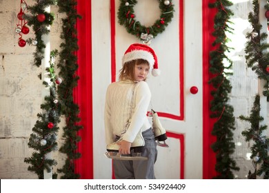 funny girl child in santa hat on the porch of a house, lifestyle, nordic, rustic style, wooden red sweater background