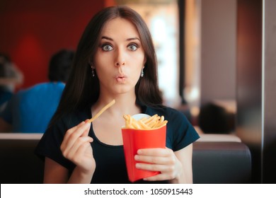 Funny Girl Eating Fries in French Fast Food Restaurant. Hungry woman having a quick unhealthy snack at a dinner 
