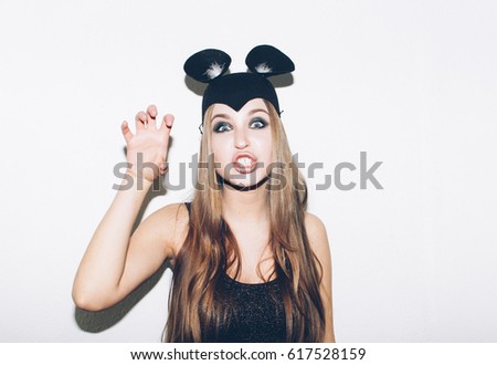 Funny girl fight with legs represents small cat or mouse. Woman with bright makeup hairstyle and night dress with raised leg mouse ears having fun. On white background not isolated