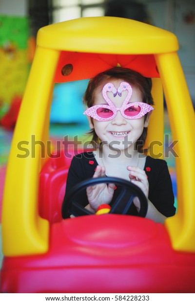 funny girl in glasses in\
the toy car