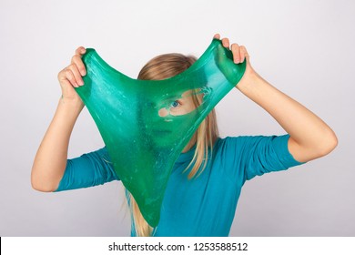 Funny girl holdin a transparent slime in front of her face and looking through its hole.