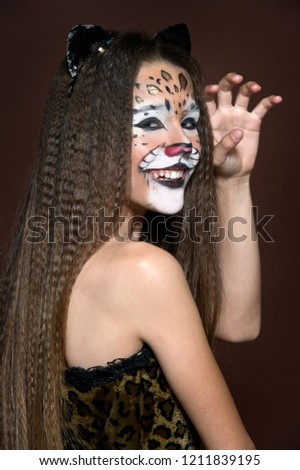 Funny Girl making face painting. Halloween makeup. Face art tiger.