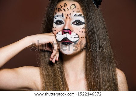 Funny Girl making face painting. Halloween makeup. Face art tiger.
