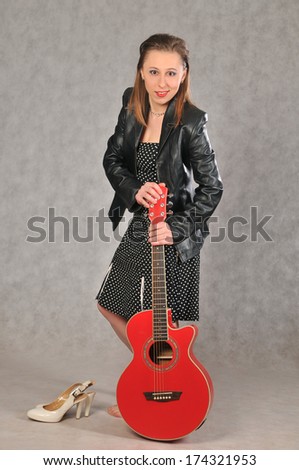 Funny girl with red guitar on gray background