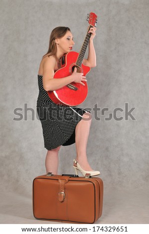 Funny girl with red guitar on gray background