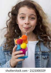 Funny girl sipping in glass with colorful pompons
