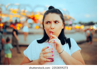 
				Funny Girl Taking a Sip from her Sweet Cheery juice. Expressive Teen Unhappy with the loud carnival 
				