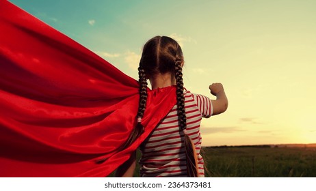 Funny girl with waving red cloak imitates flight in sunset summer field - Powered by Shutterstock