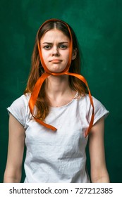 funny girl wrapped her head in orange ribbon, isolated on a green background