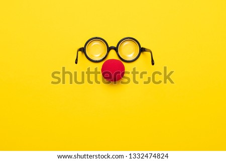 Funny glasses, a red clown nose and tie on a colored background, like a face. Flat lay. Funny costume for the holidays. Anonymous concept.