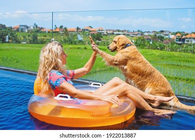 Funny golden labrador retriever give high five to happy girl swimming in pool. Fun with friends at pool party on luxury villa. Active water games with family pet, dog like companion on summer vacation - Powered by Shutterstock