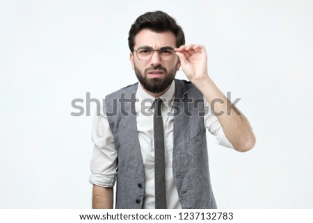 Funny good looking skeptical man in glasses looking at camera. He tries to make out the fine print on the contract.