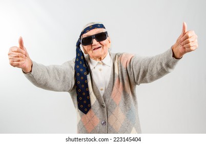 Funny grandma's studio portarit with a tie on her forehead, showing thumbs up