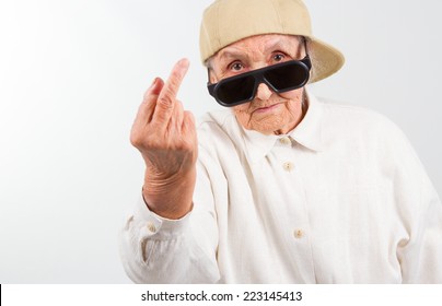 Funny grandma's studio portrait  wearing eyeglasses and baseball cap, who shows her f-finger ,  isolated on white