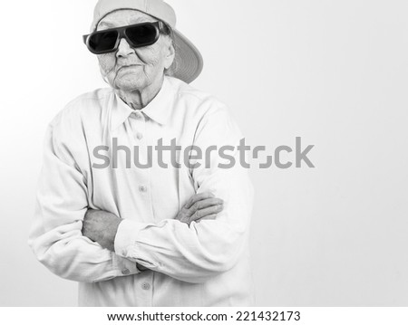 Funny grandma's studio portrait  wearing eyeglasses and baseball cap, who stands for her right,  in balck and white