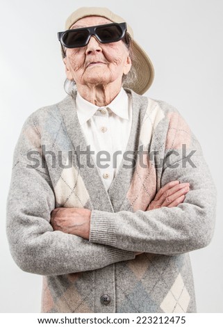 Funny grandma's studio portrait  wearing eyeglasses and baseball cap, who stands for her right,  isolated on white