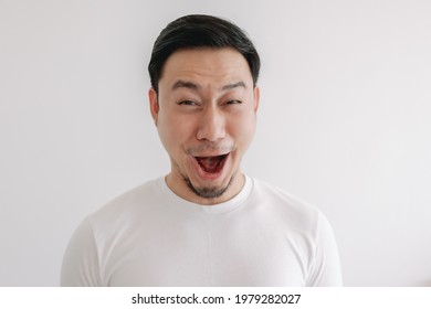 Funny grin smile face of Asian man in white t-shirt isolated on white wall.