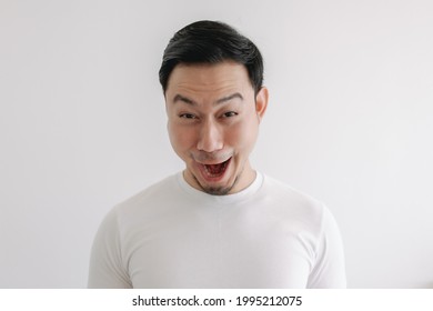 Funny grin smile face of Asian man in white t-shirt isolated on white wall.