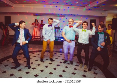 Funny Groom And Groomsmen In Different Colored Bow Ties Dance In The Restaurant Hall