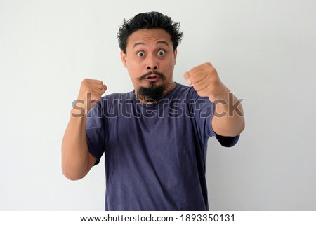 funny grumpy man with angry reaction starring at camera, mad expression of asian guy fisting a hand