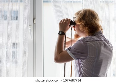 Funny Guy Looking Through Window Using Binoculars To Peek At The Neighbors.