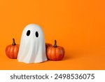 Funny Halloween ghost and Halloween pumpkins with space for text over orange background. Halloween concept background