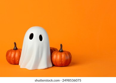 Funny Halloween ghost and Halloween pumpkins with space for text over orange background. Halloween concept background - Powered by Shutterstock