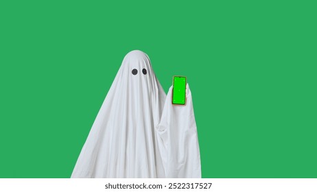 Funny halloween ghost in white sheet pointing shows thumb up at smartphone isolated on chroma key green screen background. Happy halloween spooky concept. - Powered by Shutterstock