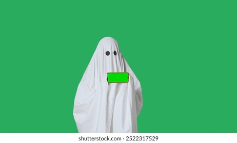 Funny halloween ghost in white sheet pointing shows thumb up at smartphone isolated on chroma key green screen background. Happy halloween spooky concept. - Powered by Shutterstock