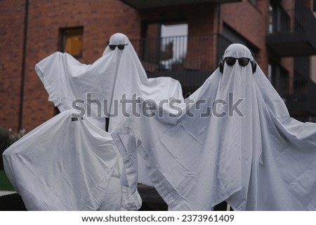Funny Halloween Kid Concept, 3 little kids with white dressed costume halloween ghost scary with sunglasses, Ghost costume for Halloween concept.  A ghost of a child under a white sheet.