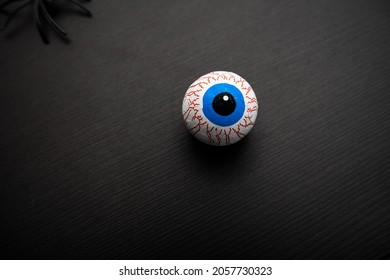 Funny halloween treat - Candy eyeballs on dark background wirh a black sipder. Copy space