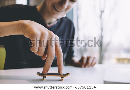 Funny and handsome guy sitting in a nice cafe near the window and playing on the table with a small toy. Smilng man is happy. Close up