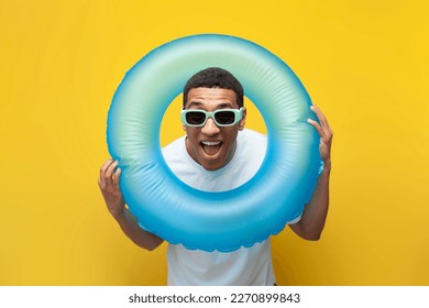 funny happy african american guy in sunglasses with inflatable swimming ring on yellow background, male tourist in the summer on sea, concept of travel and summer vacation - Powered by Shutterstock