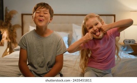 Funny happy Caucasian children kids boy girl brother sister siblings son daughter friends teasing camera at home grimacing playing together fooling around making faces showing tongue joking in bedroom - Powered by Shutterstock