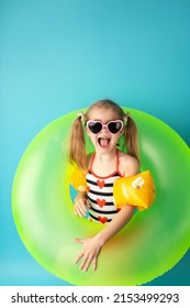 Funny Happy Child In Bright Swimsuit And Sun Glasses Smiling And Holding A Swimming Ring On Colored Background. Summer And Vacation Concept.