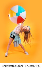 Funny Happy Child In Summer Clothes Jumping With Beachball On Colored Background