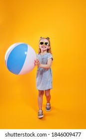 Funny Happy Child In Sunglasses Holding Beachball On Yellow Background