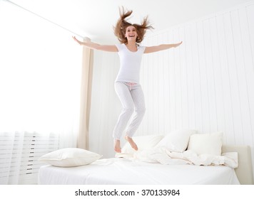 funny happy girl jumping and having fun in bed