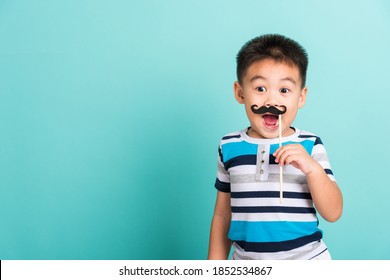 Funny happy hipster kid holding black mustache props for the photo booth close face, studio shot isolated on a blue background, Men health awareness, Prostate Cancer Awareness - Powered by Shutterstock