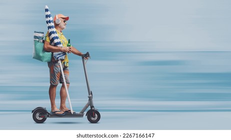 Funny happy senior tourist going to the beach, he is holding a beach umbrella and riding a fast electric scooter - Powered by Shutterstock