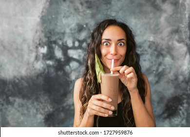 Funny Happy Woman Drinking Chocolate Milk Shake With Cocoa And Laughing. Summer Drink Concept. Gray Concrete Wall Background.