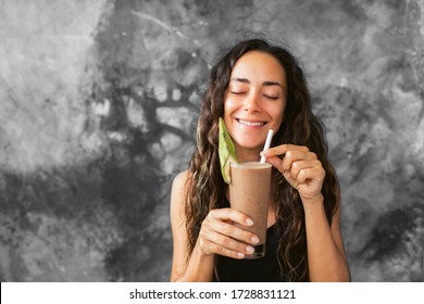 Funny Happy Woman Drinking Chocolate Milk Shake With Cocoa And Laughing. Summer Drink Concept. Gray Concrete Wall Background.