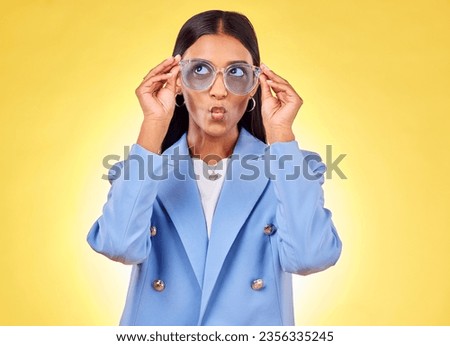 Funny, happy woman and sunglasses with kiss, comedy and silly face in a studio. Yellow background, pout and young female person with modern fashion, trendy cool style and creative work clothing