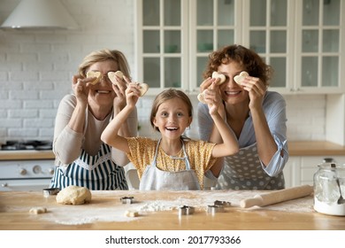 Funny head shot portrait happy three generations of women cooking sweet homemade cookies, having fun with dough, cute little girl with mature grandmother and mother spending leisure time together - Powered by Shutterstock