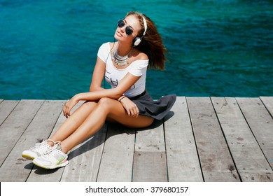 Funny Hipster Girl in urban street,hipster outfit Going Crazy at tropical island,windy day Background.Trendy Casual Fashion Outfit in summer,spring.Toned Photo,Copy Space.music on cool big headphones