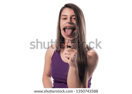 Funny image of happy excited female smiling and showing tongue through a magnifying glass, over white background