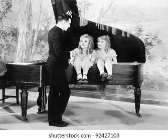 Funny Image Of Twins Sitting Inside Of A Piano Talking To A Young Man